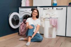 woman-sitting-washing-machine-with-basket-full-clothes